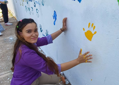 Joven estudiante pintando sus manos en un mural