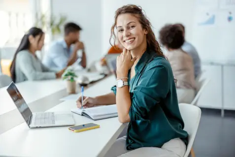 Una mujer sentada en una mesa con su portátil.