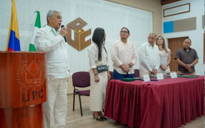 Hombre pronunciando un discurso en un podio de la UPC frente a una mesa de honor durante una ceremonia institucional.