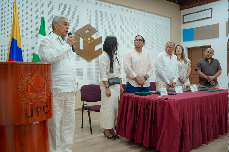 Hombre pronunciando un discurso en un podio de la UPC frente a una mesa de honor durante una ceremonia institucional.